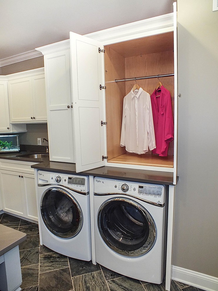 Photo of a large contemporary galley separated utility room in Cleveland with white cabinets, ceramic flooring, a side by side washer and dryer, shaker cabinets and grey walls.