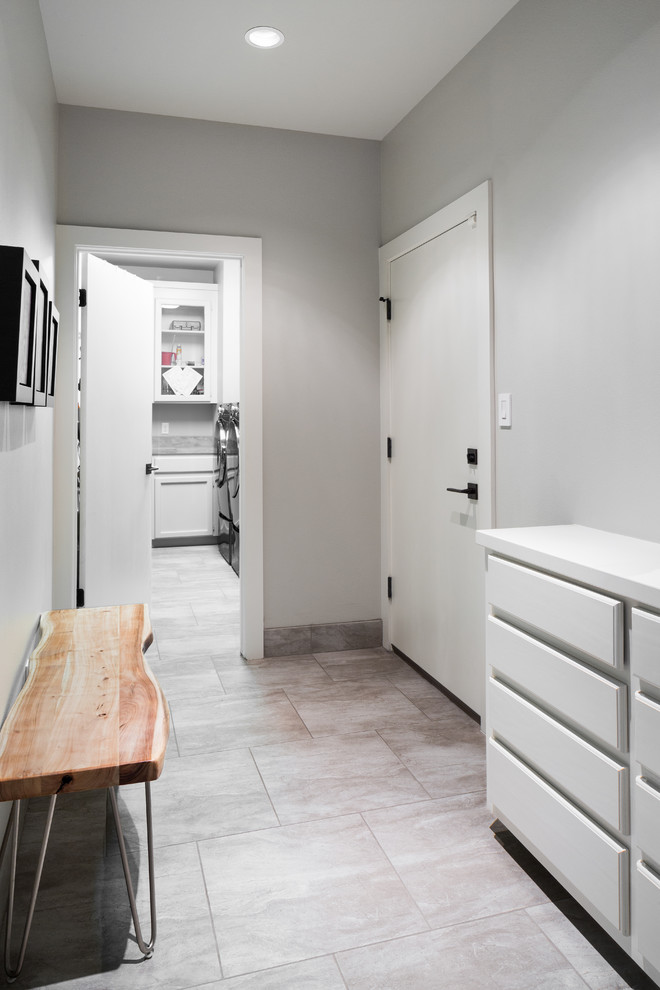 Immagine di una sala lavanderia tradizionale con ante con bugna sagomata, ante bianche, top in legno, pareti grigie, pavimento in gres porcellanato e lavatrice e asciugatrice affiancate