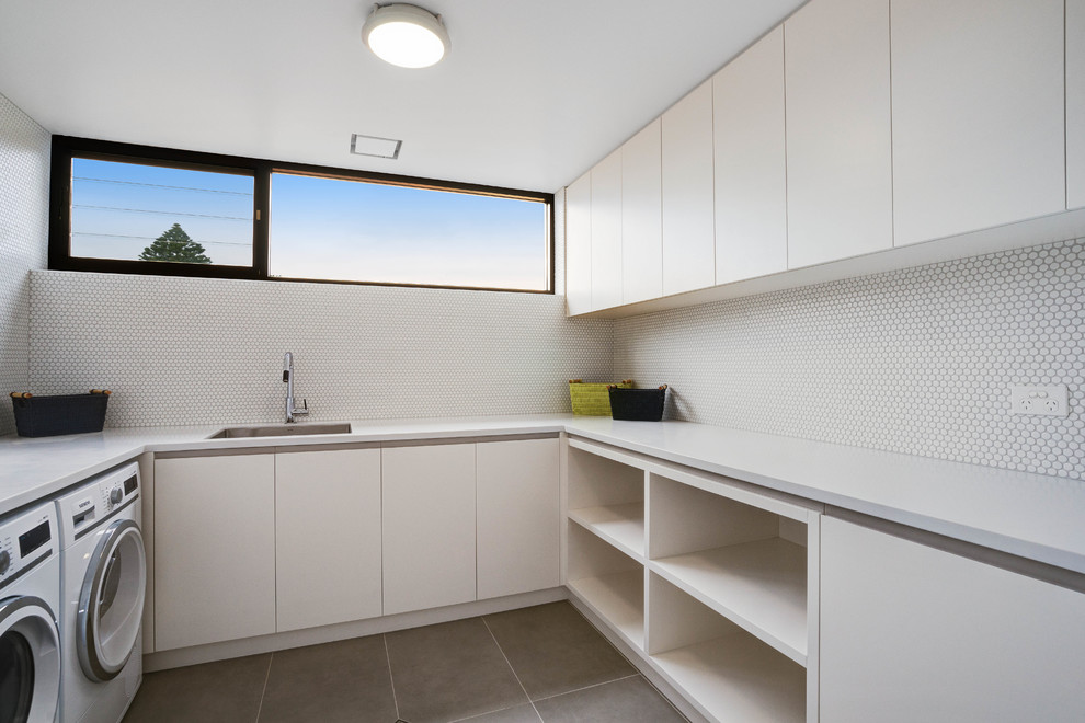 Foto di una sala lavanderia design di medie dimensioni con lavello sottopiano, ante lisce, ante bianche, top in superficie solida e top bianco