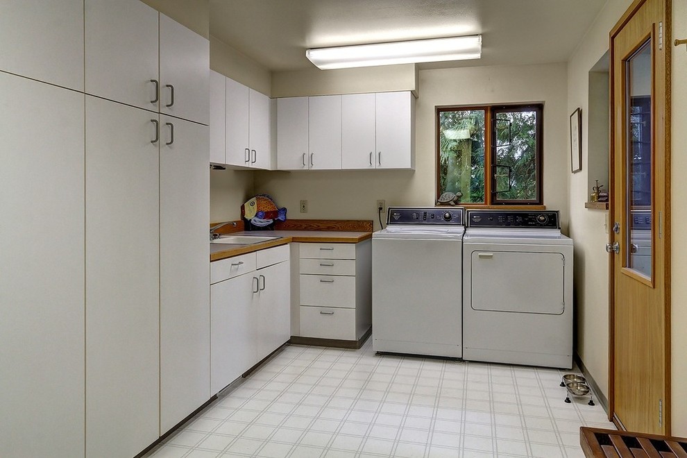 Example of a mid-sized classic l-shaped linoleum floor utility room design in Seattle with a single-bowl sink, flat-panel cabinets, beige walls and a side-by-side washer/dryer