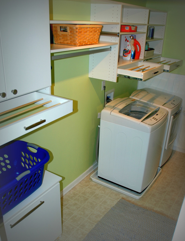 Inredning av en modern stor linjär tvättstuga enbart för tvätt, med släta luckor, vita skåp, gröna väggar, linoleumgolv och en tvättmaskin och torktumlare bredvid varandra