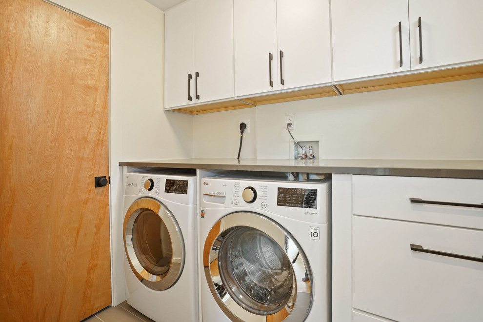 Foto de cuarto de lavado lineal moderno pequeño con armarios con paneles lisos, puertas de armario blancas, paredes beige, suelo de baldosas de porcelana, lavadora y secadora juntas y suelo gris