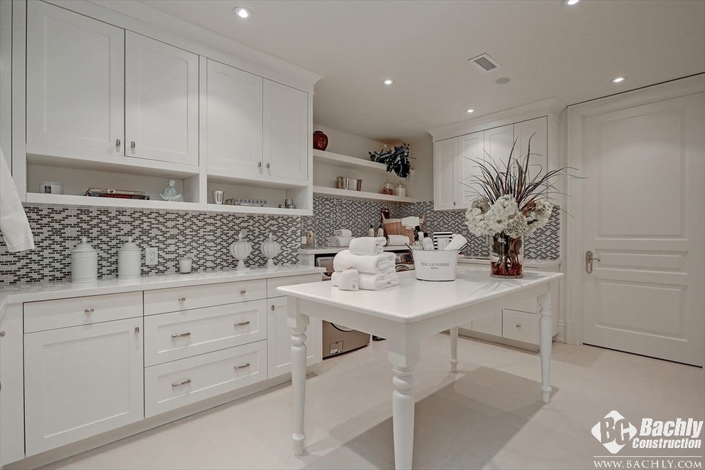 Example of a large classic single-wall dedicated laundry room design in Toronto with recessed-panel cabinets, white cabinets, marble countertops, white walls and a side-by-side washer/dryer