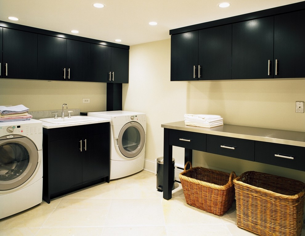 Modern inredning av en tvättstuga, med svarta skåp och beiget golv