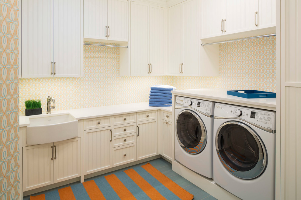 Modelo de cuarto de lavado en L marinero con fregadero sobremueble, puertas de armario blancas, paredes multicolor, lavadora y secadora juntas y encimeras blancas