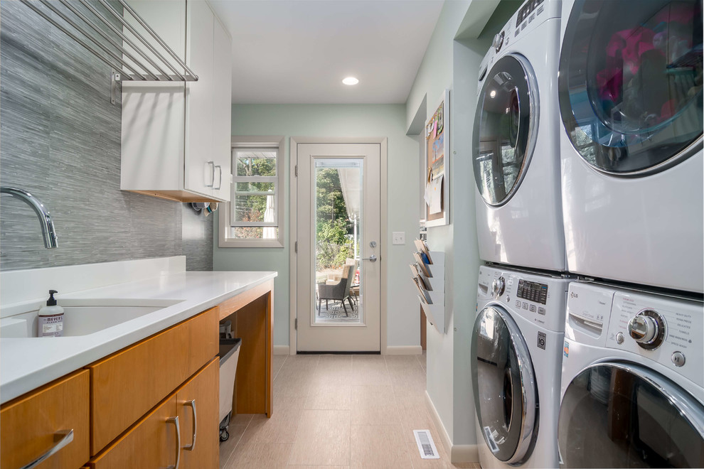 Exempel på en mellanstor klassisk parallell tvättstuga enbart för tvätt, med en enkel diskho, släta luckor, skåp i ljust trä, granitbänkskiva, blå väggar, klinkergolv i keramik, en tvättpelare och beiget golv