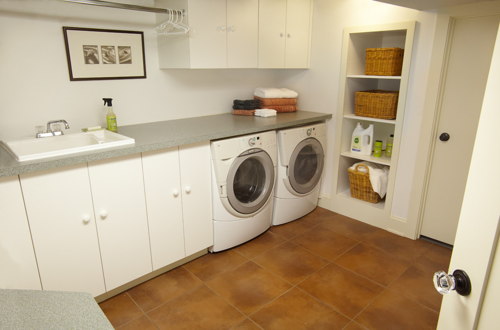 Idéer för små amerikanska l-formade tvättstugor enbart för tvätt, med en nedsänkt diskho, släta luckor, laminatbänkskiva, vita väggar, klinkergolv i keramik och en tvättmaskin och torktumlare bredvid varandra