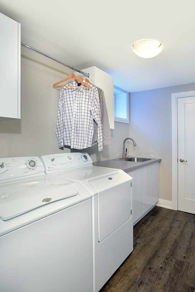 Foto di una sala lavanderia moderna di medie dimensioni con lavello a vasca singola, ante lisce, ante bianche, top in quarzo composito, pareti grigie e lavatrice e asciugatrice affiancate