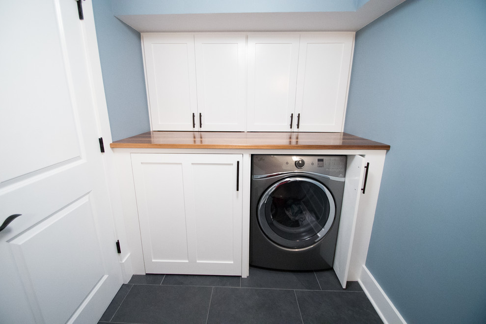 Design ideas for a medium sized classic single-wall separated utility room in New York with blue walls, shaker cabinets, white cabinets, wood worktops, slate flooring and a side by side washer and dryer.