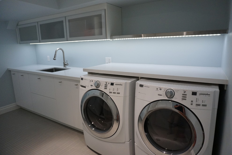 Esempio di una lavanderia multiuso minimalista con lavello sottopiano, ante lisce, ante bianche, top in quarzo composito, pareti blu, pavimento in gres porcellanato e lavatrice e asciugatrice affiancate