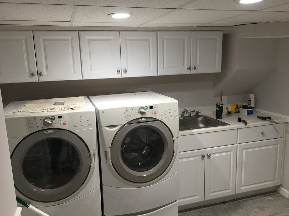 Immagine di una sala lavanderia minimalista con lavello da incasso, ante con bugna sagomata, ante bianche, pareti grigie, lavatrice e asciugatrice affiancate e pavimento con piastrelle in ceramica