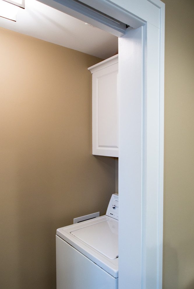Photo of a medium sized traditional galley separated utility room in Detroit with flat-panel cabinets, white cabinets, beige walls, ceramic flooring and a side by side washer and dryer.