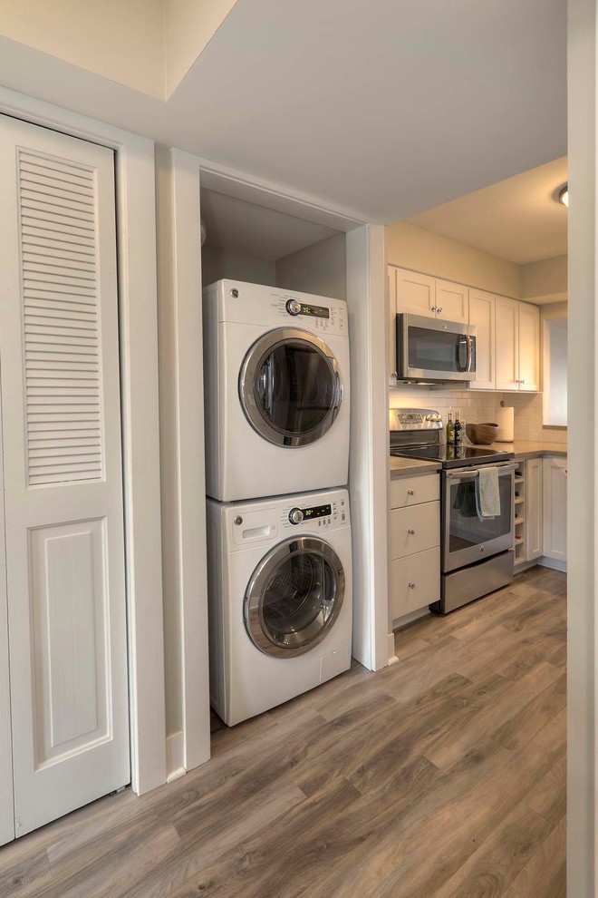 Foto di un piccolo ripostiglio-lavanderia chic con pareti beige, pavimento in vinile e lavatrice e asciugatrice a colonna