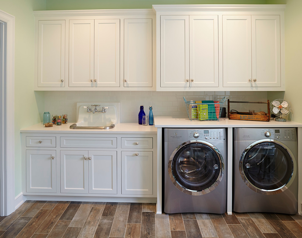 Inspiration for a coastal single-wall brown floor laundry room remodel in Minneapolis with green walls, a drop-in sink, recessed-panel cabinets, white cabinets, a side-by-side washer/dryer and white countertops