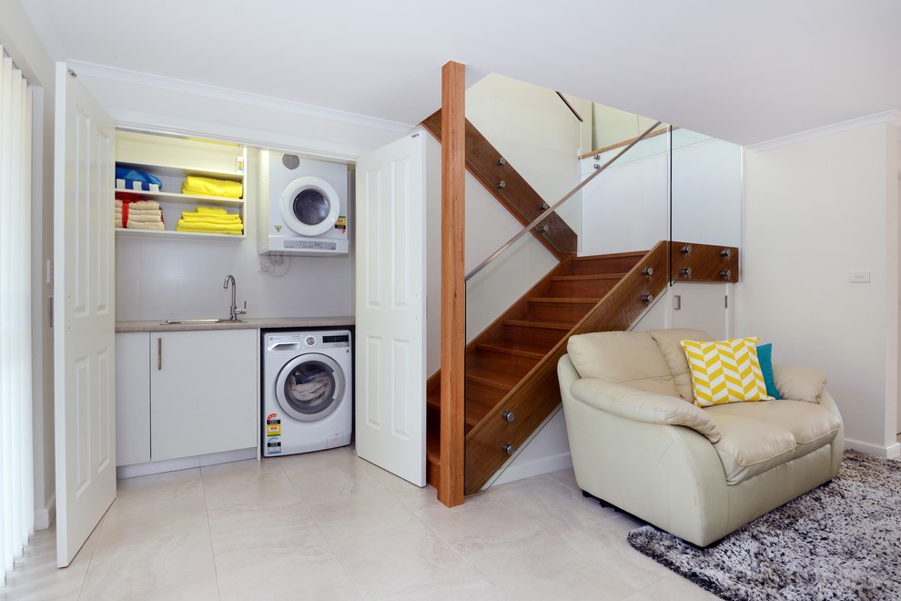 Idee per un piccolo ripostiglio-lavanderia minimal con lavello da incasso, pareti bianche, pavimento in marmo e lavatrice e asciugatrice a colonna