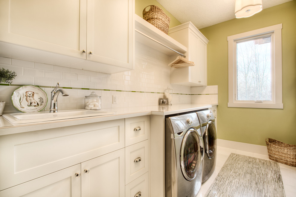 Idéer för att renovera en stor vintage linjär tvättstuga enbart för tvätt, med en nedsänkt diskho, skåp i shakerstil, vita skåp, laminatbänkskiva, gröna väggar, marmorgolv och en tvättmaskin och torktumlare bredvid varandra