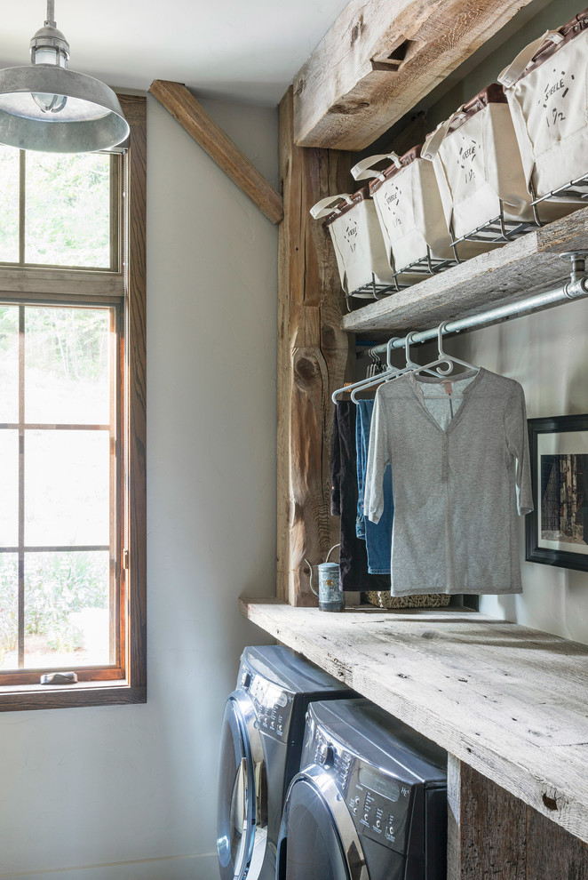 Foto på en mellanstor rustik tvättstuga enbart för tvätt, med öppna hyllor, skåp i mellenmörkt trä, träbänkskiva, vita väggar, mörkt trägolv, en tvättmaskin och torktumlare bredvid varandra och grått golv