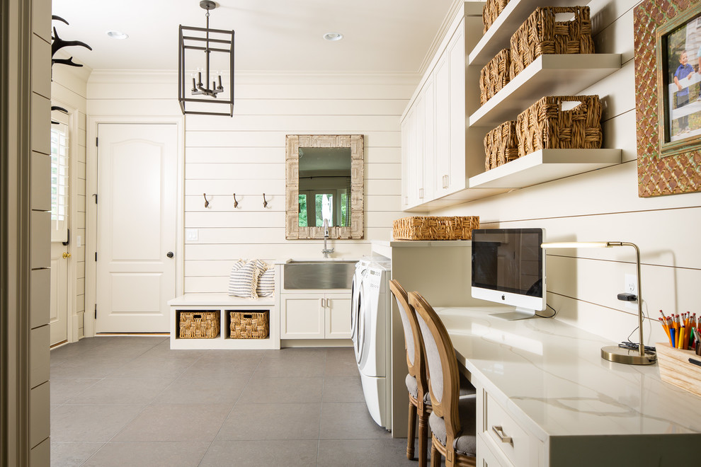 アトランタにある高級な巨大なカントリー風のおしゃれな家事室 (L型、エプロンフロントシンク、落し込みパネル扉のキャビネット、白いキャビネット、珪岩カウンター、白い壁、左右配置の洗濯機・乾燥機、グレーの床、白いキッチンカウンター) の写真