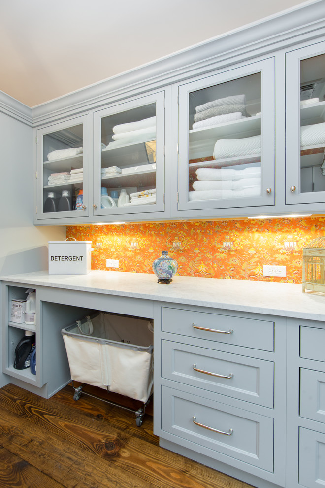 Laundry room - large transitional laundry room idea in Boston with a stacked washer/dryer, recessed-panel cabinets, marble countertops and gray cabinets