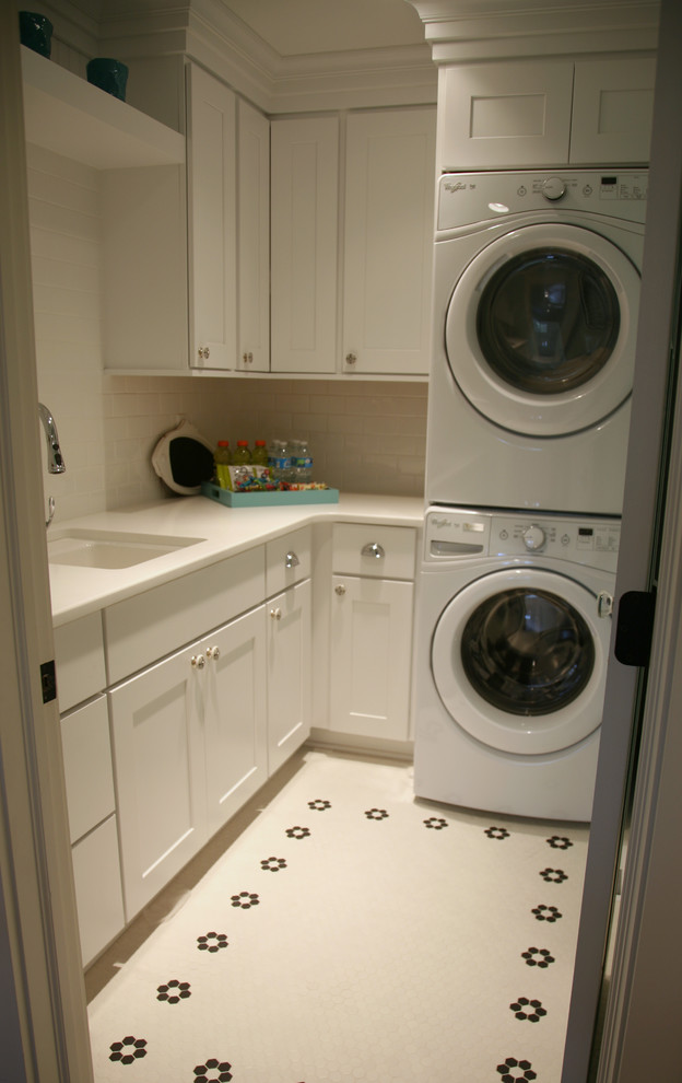 Foto på en liten vintage l-formad tvättstuga enbart för tvätt, med en undermonterad diskho, luckor med infälld panel, vita skåp, bänkskiva i kvarts, vita väggar, klinkergolv i porslin och en tvättpelare