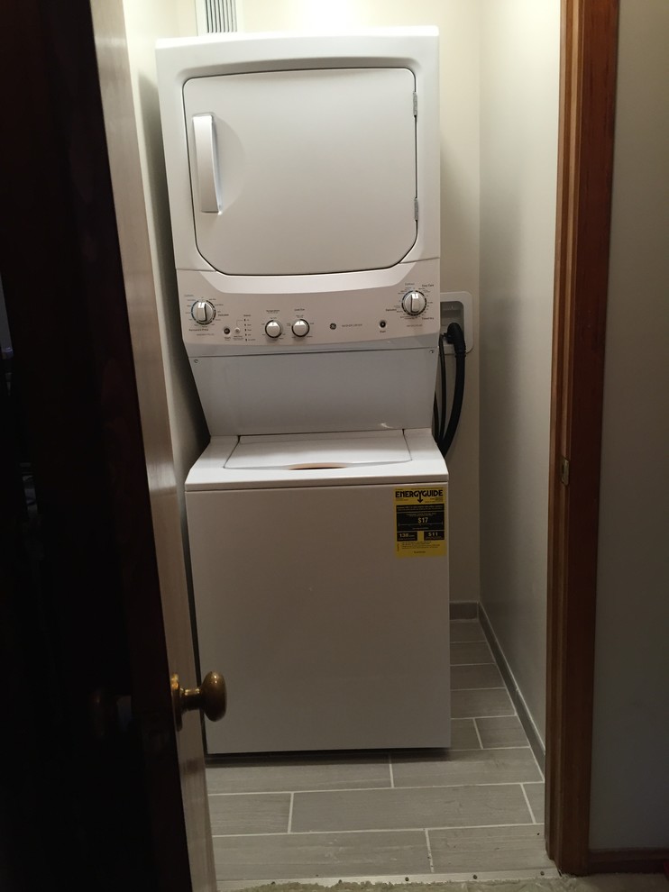 Example of a small single-wall porcelain tile laundry closet design in Louisville with white walls and a stacked washer/dryer