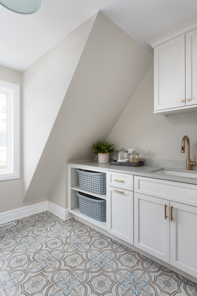 Inspiration for a large transitional galley porcelain tile and gray floor dedicated laundry room remodel in Chicago with an undermount sink, flat-panel cabinets, white cabinets, quartz countertops, beige walls, a side-by-side washer/dryer and gray countertops