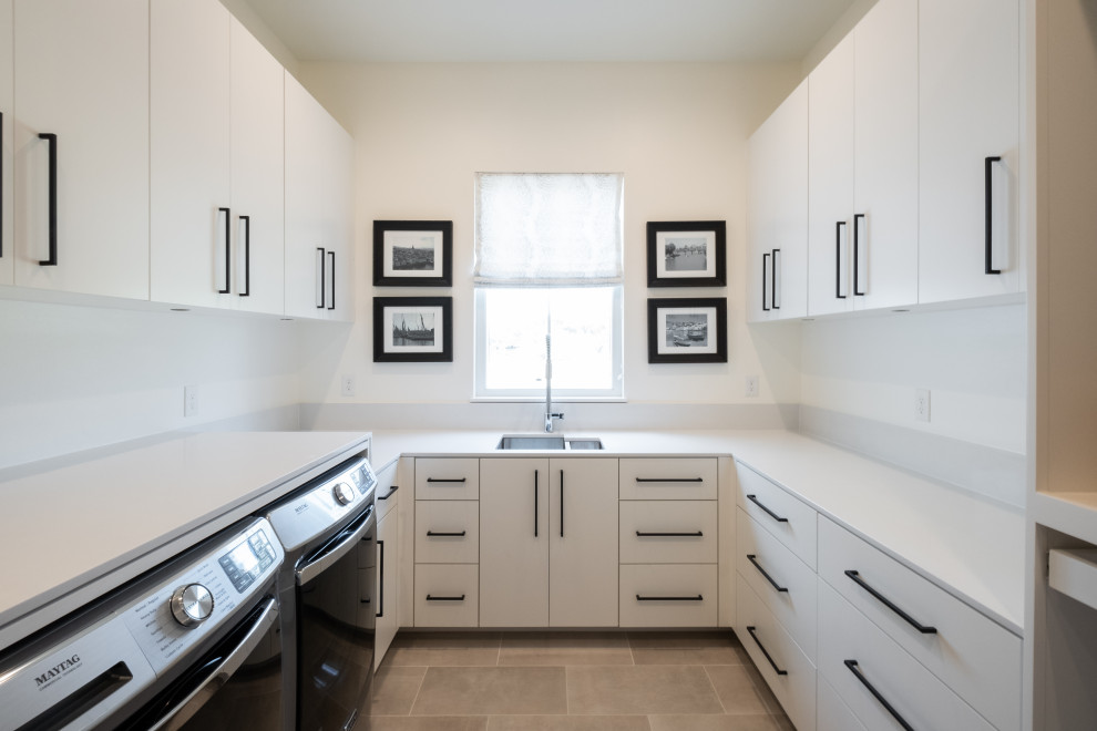 オースティンにあるラグジュアリーな中くらいなコンテンポラリースタイルのおしゃれな家事室 (コの字型、アンダーカウンターシンク、フラットパネル扉のキャビネット、白いキャビネット、珪岩カウンター、白いキッチンパネル、白い壁、セラミックタイルの床、左右配置の洗濯機・乾燥機、ベージュの床、白いキッチンカウンター) の写真