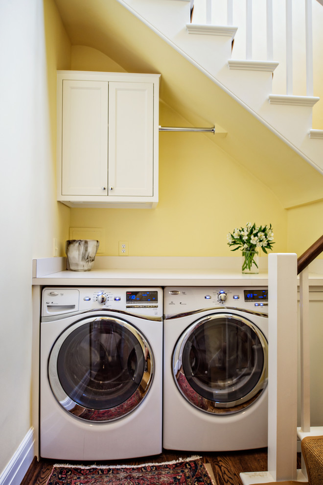 ナッシュビルにある高級な小さなトラディショナルスタイルのおしゃれな家事室 (I型、落し込みパネル扉のキャビネット、白いキャビネット、ラミネートカウンター、黄色い壁、無垢フローリング、左右配置の洗濯機・乾燥機) の写真