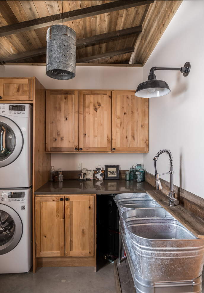 Inredning av en rustik mellanstor grå l-formad grått tvättstuga enbart för tvätt, med en allbänk, skåp i shakerstil, vita väggar, en tvättpelare, grått golv, betonggolv, skåp i mellenmörkt trä och bänkskiva i koppar