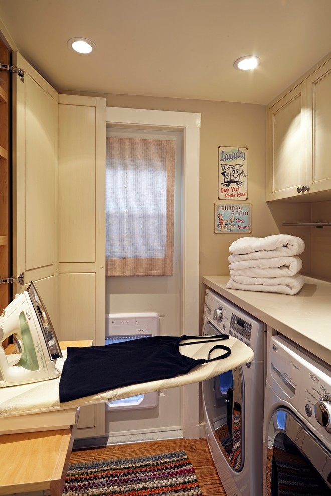 Laundry room - small traditional medium tone wood floor laundry room idea in Los Angeles with recessed-panel cabinets, beige walls and beige cabinets