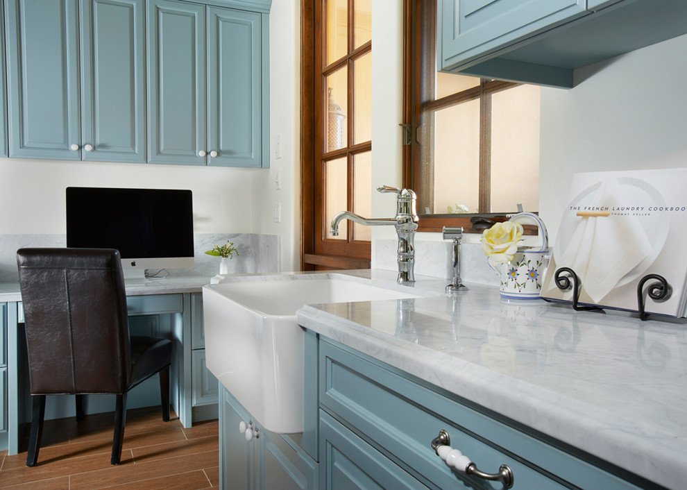 Inspiration för mellanstora medelhavsstil linjära tvättstugor enbart för tvätt, med marmorbänkskiva, blå skåp, vita väggar, en rustik diskho och vitt golv
