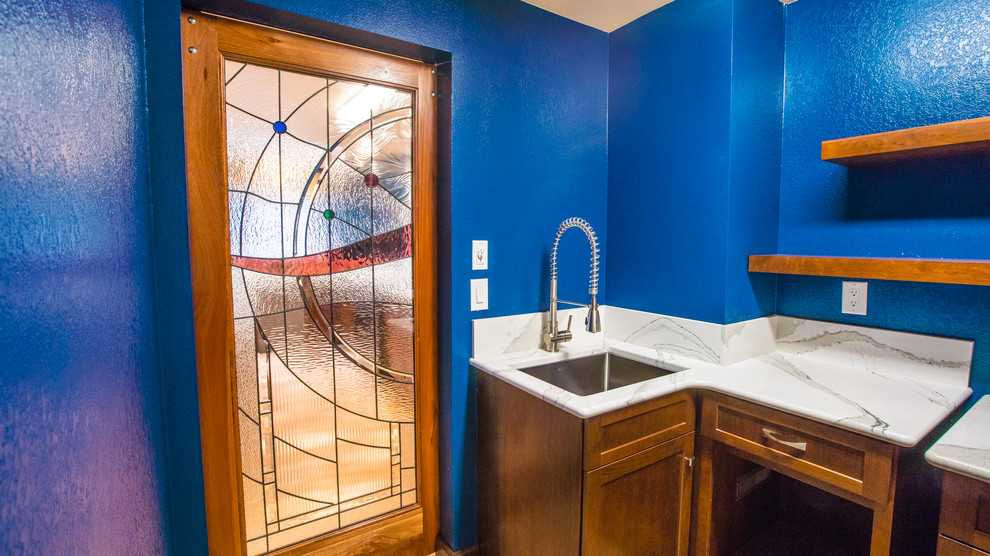 Example of a large laminate floor laundry room design in Seattle with an undermount sink, recessed-panel cabinets, dark wood cabinets, quartz countertops, blue walls and a stacked washer/dryer