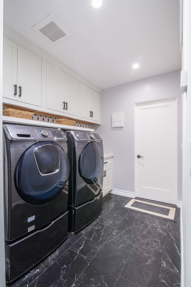 Exempel på en mellanstor modern linjär tvättstuga enbart för tvätt, med skåp i shakerstil, vita skåp, bänkskiva i kvarts, grå väggar, klinkergolv i porslin, en tvättmaskin och torktumlare bredvid varandra och svart golv