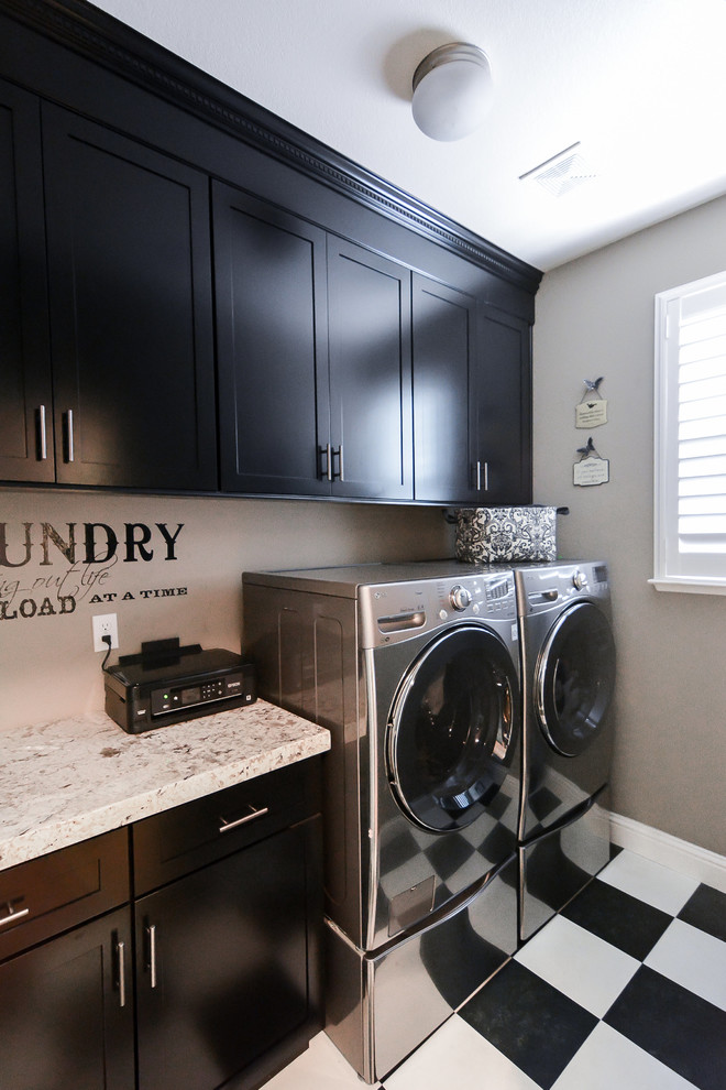 Immagine di una sala lavanderia classica di medie dimensioni con ante in stile shaker, ante nere, top in granito, pareti grigie, pavimento in linoleum e lavatrice e asciugatrice affiancate