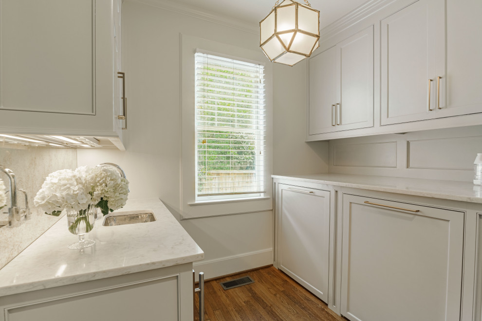 Example of a small transitional galley dark wood floor and brown floor utility room design in Other with beaded inset cabinets, gray cabinets, marble countertops, metallic backsplash, mirror backsplash, white walls, a side-by-side washer/dryer and white countertops