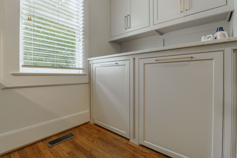 Photo of a small traditional galley utility room in Other with beaded cabinets, grey cabinets, marble worktops, metallic splashback, mirror splashback, white walls, dark hardwood flooring, a side by side washer and dryer, brown floors and white worktops.