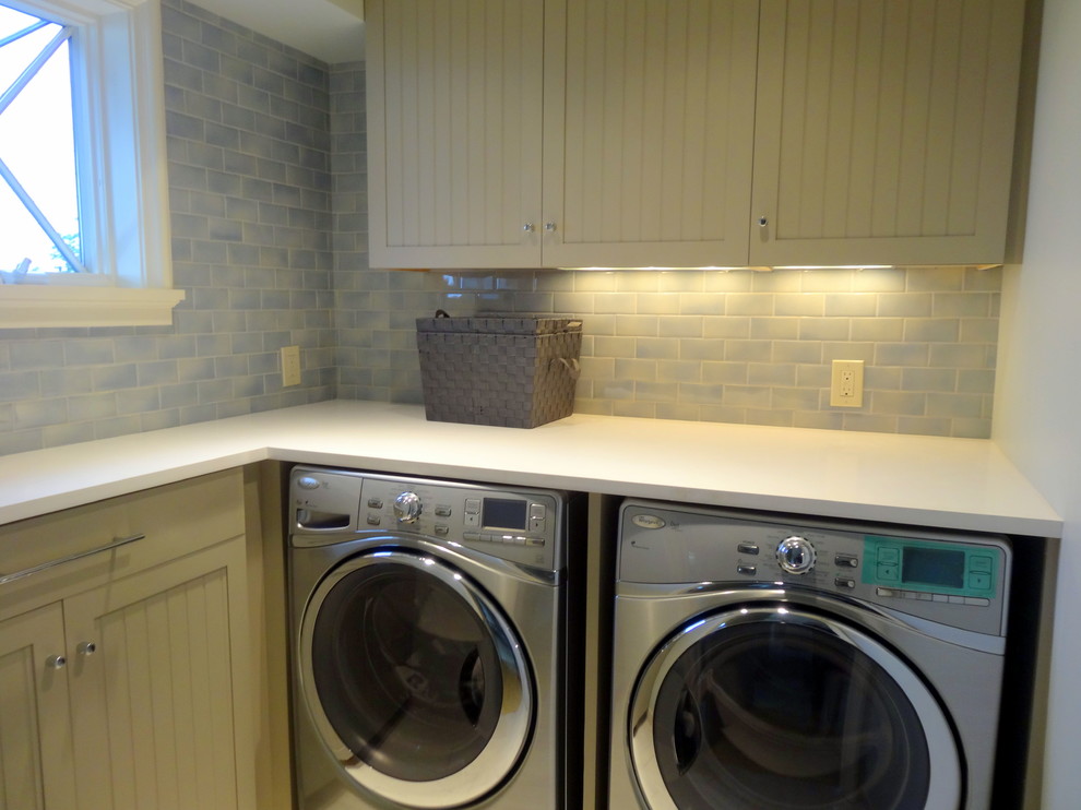 Exempel på en liten modern l-formad tvättstuga enbart för tvätt, med beige skåp, laminatbänkskiva, en tvättmaskin och torktumlare bredvid varandra, blå väggar, klinkergolv i keramik och luckor med infälld panel