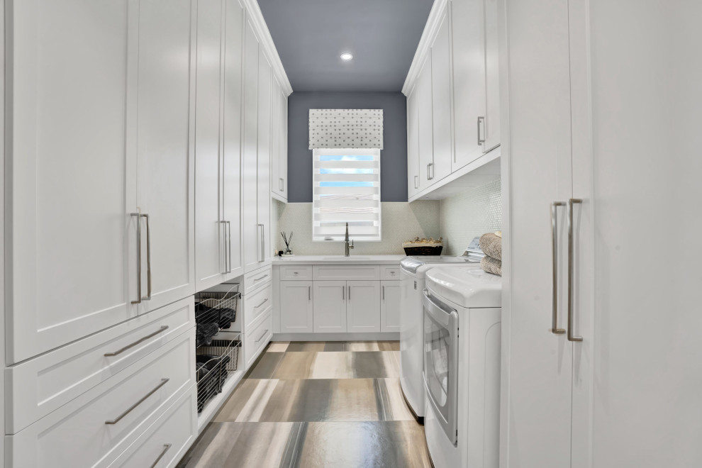 Idéer för stora funkis u-formade vitt tvättstugor enbart för tvätt, med en undermonterad diskho, skåp i shakerstil, vita skåp, bänkskiva i koppar, vitt stänkskydd, stänkskydd i marmor, blå väggar, klinkergolv i keramik, en tvättmaskin och torktumlare bredvid varandra och blått golv