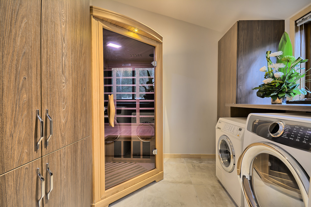Medium sized traditional galley utility room in Montreal with flat-panel cabinets, medium wood cabinets, grey walls, ceramic flooring, laminate countertops and a side by side washer and dryer.