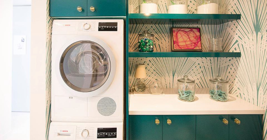 Einzeilige, Kleine Moderne Waschküche mit flächenbündigen Schrankfronten, Laminat-Arbeitsplatte, bunten Wänden, Waschmaschine und Trockner gestapelt und blauen Schränken in Houston
