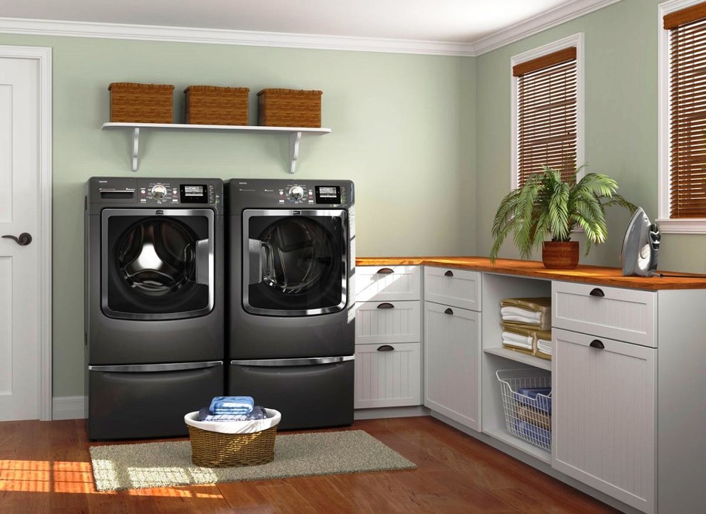 Esempio di una sala lavanderia minimal di medie dimensioni con ante in stile shaker, ante bianche, top in legno, pareti verdi, pavimento in legno massello medio, lavatrice e asciugatrice affiancate, pavimento marrone e top marrone