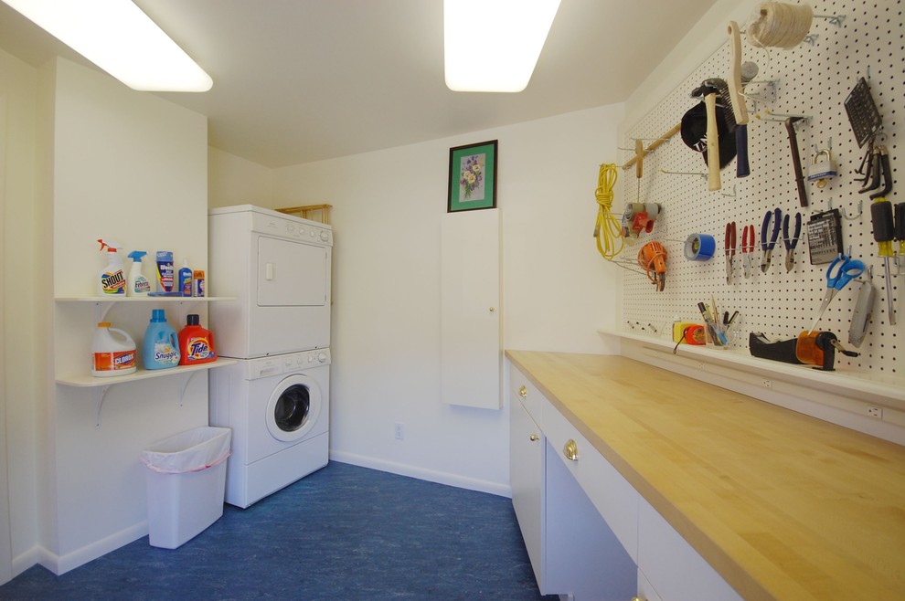 ボストンにある中くらいなトラディショナルスタイルのおしゃれな洗濯室 (コの字型、フラットパネル扉のキャビネット、白いキャビネット、木材カウンター、白い壁、リノリウムの床、上下配置の洗濯機・乾燥機、青い床) の写真
