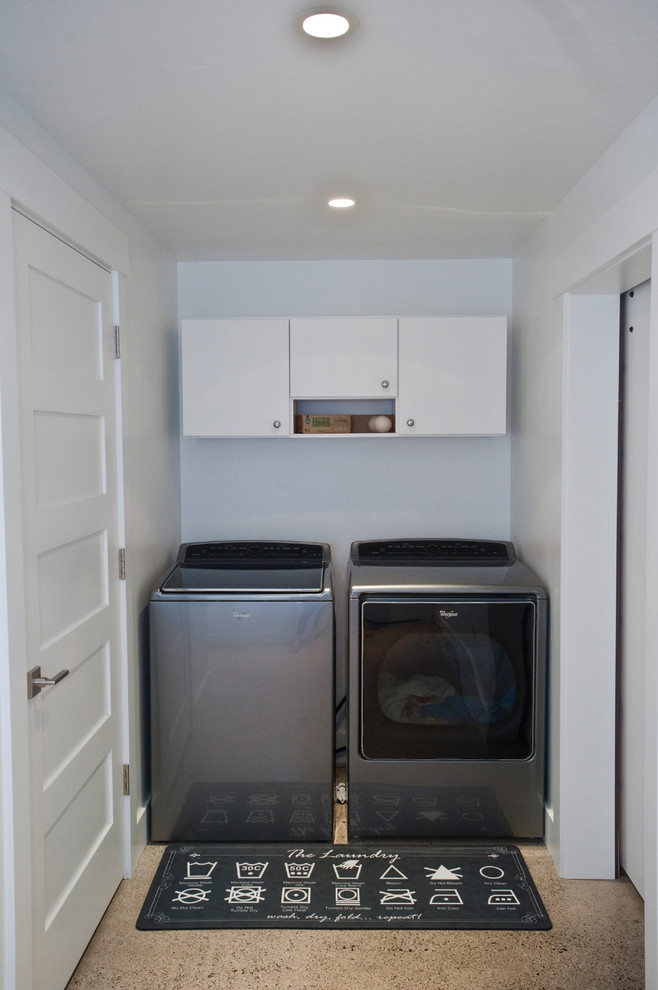 Example of a large trendy concrete floor and gray floor dedicated laundry room design in Other with flat-panel cabinets, white cabinets, quartz countertops, white walls and a side-by-side washer/dryer