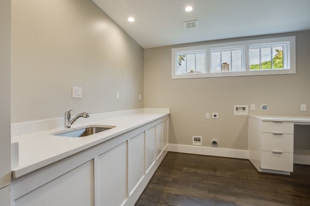 Foto di una sala lavanderia minimalista di medie dimensioni con lavello sottopiano, pareti beige, pavimento in legno massello medio e pavimento marrone