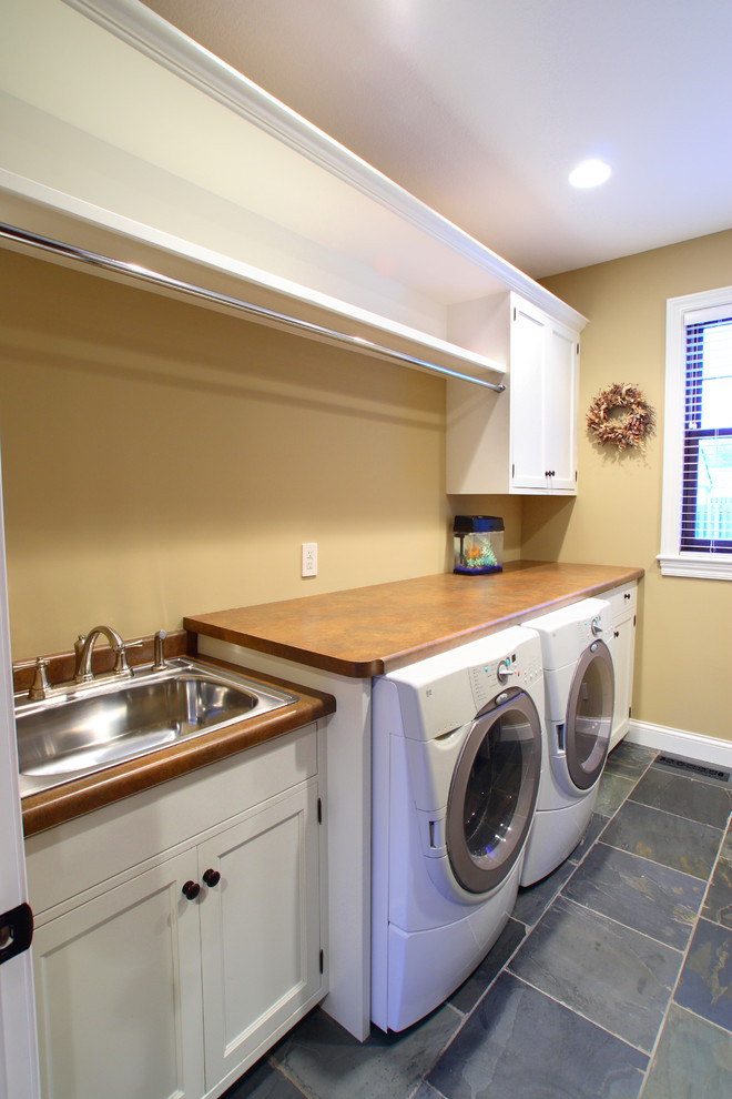 Esempio di una grande sala lavanderia stile americano con lavello da incasso, ante lisce, ante bianche, top in laminato, pavimento in ardesia, lavatrice e asciugatrice affiancate e pareti marroni