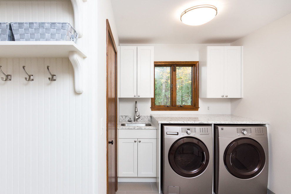 Example of a mid-sized country single-wall porcelain tile and brown floor dedicated laundry room design in Detroit with an undermount sink, beaded inset cabinets, white cabinets, quartzite countertops, gray walls and a side-by-side washer/dryer