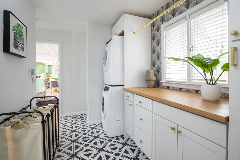 Design ideas for a medium sized traditional galley separated utility room in Indianapolis with shaker cabinets, white cabinets, wood worktops, black splashback, window splashback, white walls, ceramic flooring, a stacked washer and dryer, black floors, brown worktops and wallpapered walls.