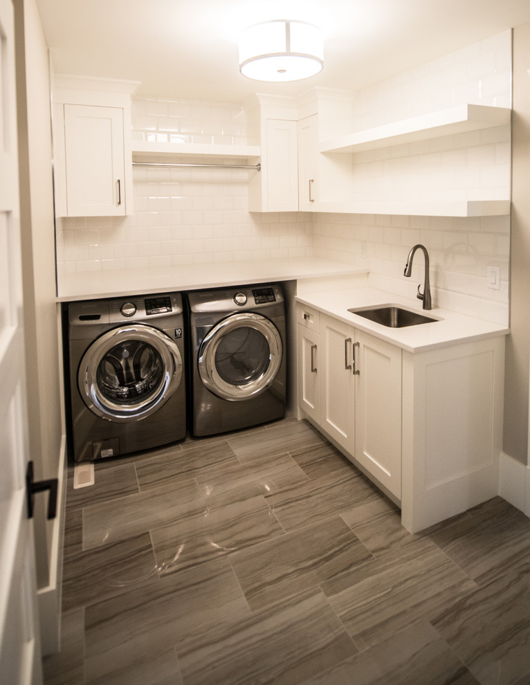Mittelgroße Klassische Waschküche in L-Form mit Unterbauwaschbecken, Schrankfronten im Shaker-Stil, weißen Schränken, Quarzwerkstein-Arbeitsplatte, beiger Wandfarbe, Porzellan-Bodenfliesen und Waschmaschine und Trockner nebeneinander in Calgary