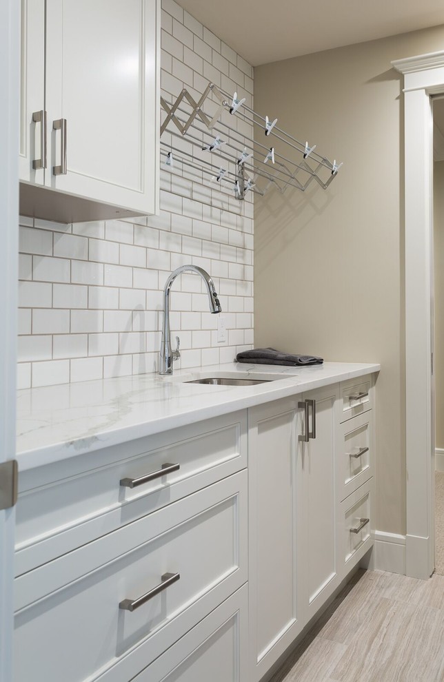 Einzeilige, Mittelgroße Klassische Waschküche mit Unterbauwaschbecken, Schrankfronten mit vertiefter Füllung, weißen Schränken, Marmor-Arbeitsplatte, beiger Wandfarbe und hellem Holzboden in Calgary