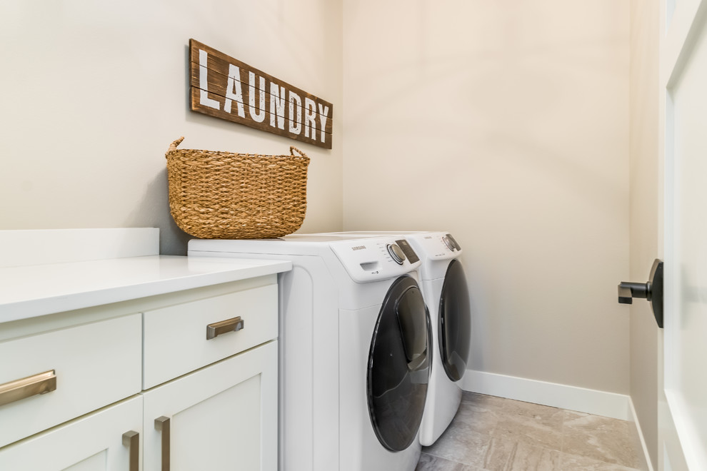 Bild på en mellanstor vintage vita linjär vitt tvättstuga enbart för tvätt, med skåp i shakerstil, vita skåp, marmorbänkskiva, beige väggar, klinkergolv i porslin, en tvättmaskin och torktumlare bredvid varandra och brunt golv